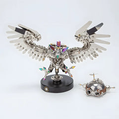 The finished Mechanical Owl on its base, shown next to a spare or alternative metal head component, all on a white background
