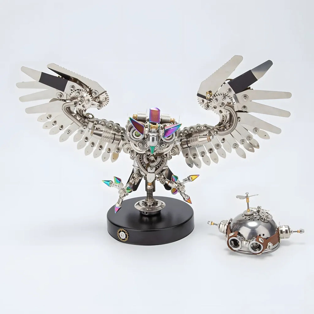 The finished Mechanical Owl on its base, shown next to a spare or alternative metal head component, all on a white background