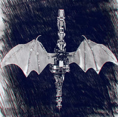 Top view of the DIY 3D metal dragon puzzle with grey wings against a textured dark background, showcasing the wingspan.